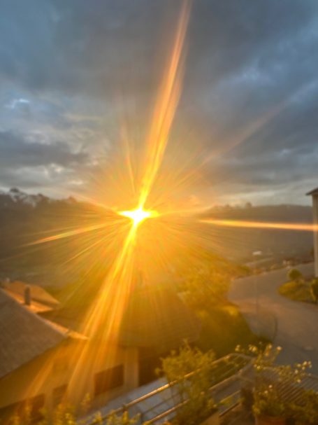 Abendstimmung in Triesenberg Sonnenuntergang mit strahlendem Licht über einer Landschaft und dunklen Wolken.